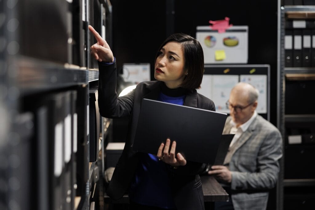 IT manager with laptop in server room attempting to restore data from backup after breach
