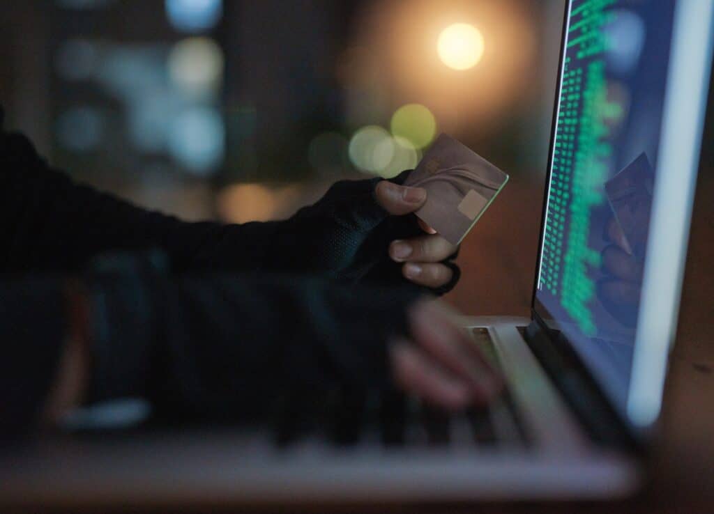 Graphic of person holding credit card up to computer screen to represent ransomware attack and lost revenue
